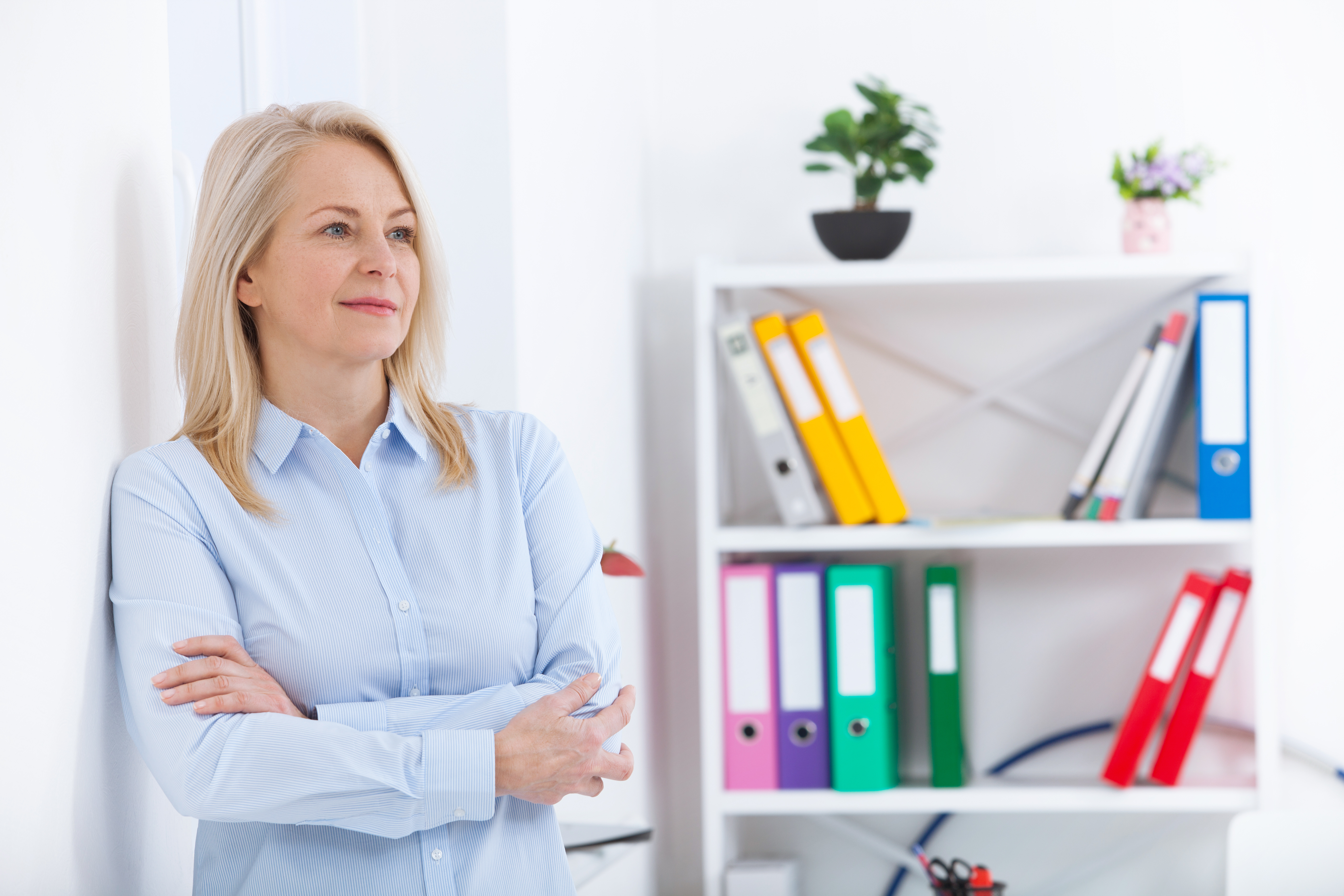 Senior professional standing beside a cabinet shelf.